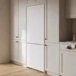 Combină frigorifică îngustă așezată într-o nișă de bucătărie, aliniată cu frontul mobilierului