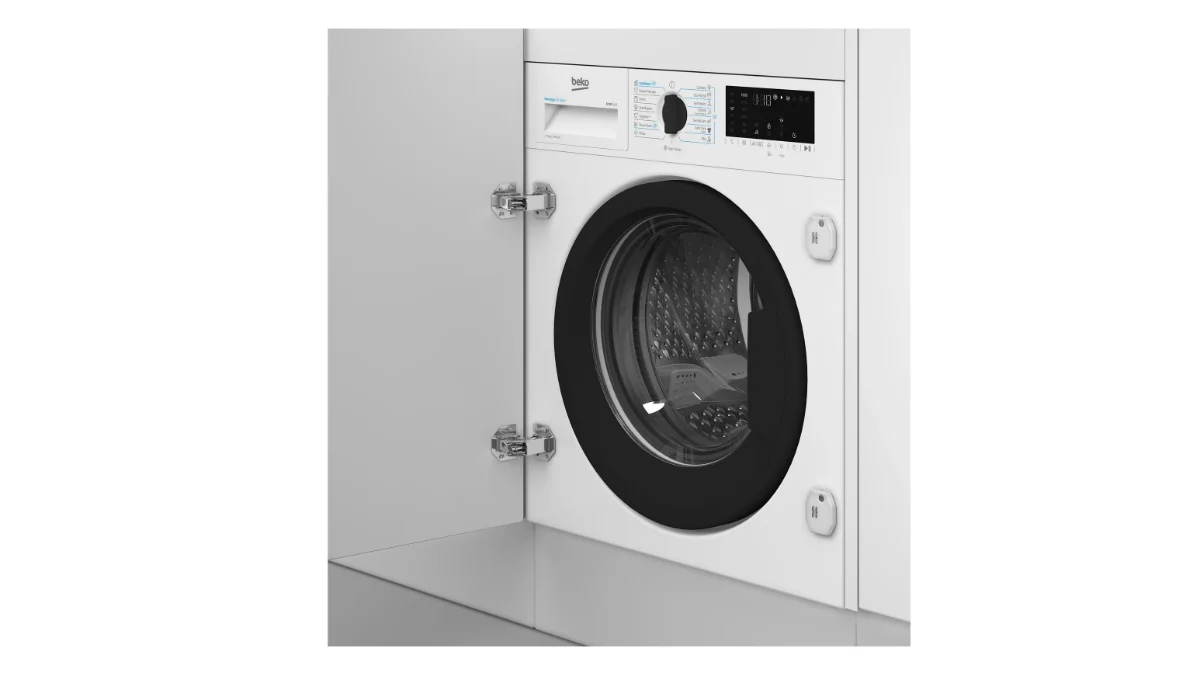 Mașina de spălat rufe incorporabilă Beko B3WBT671415W, albă, montată într-un corp de mobilier alb cu ușa deschisă, văzută din trei sferturi
