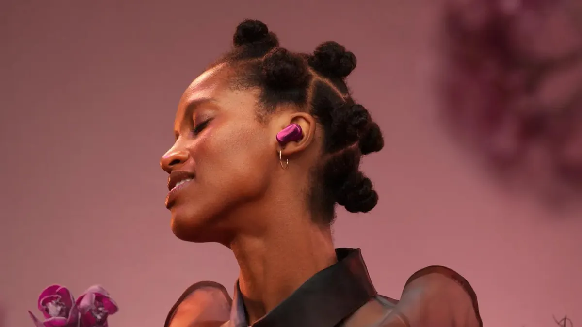 Femeie cu ochii închiși, purtând o cască in-ear Bose QuietComfort Ultra Earbuds (2nd Gen) violetă, văzută din profil pe fundal roz