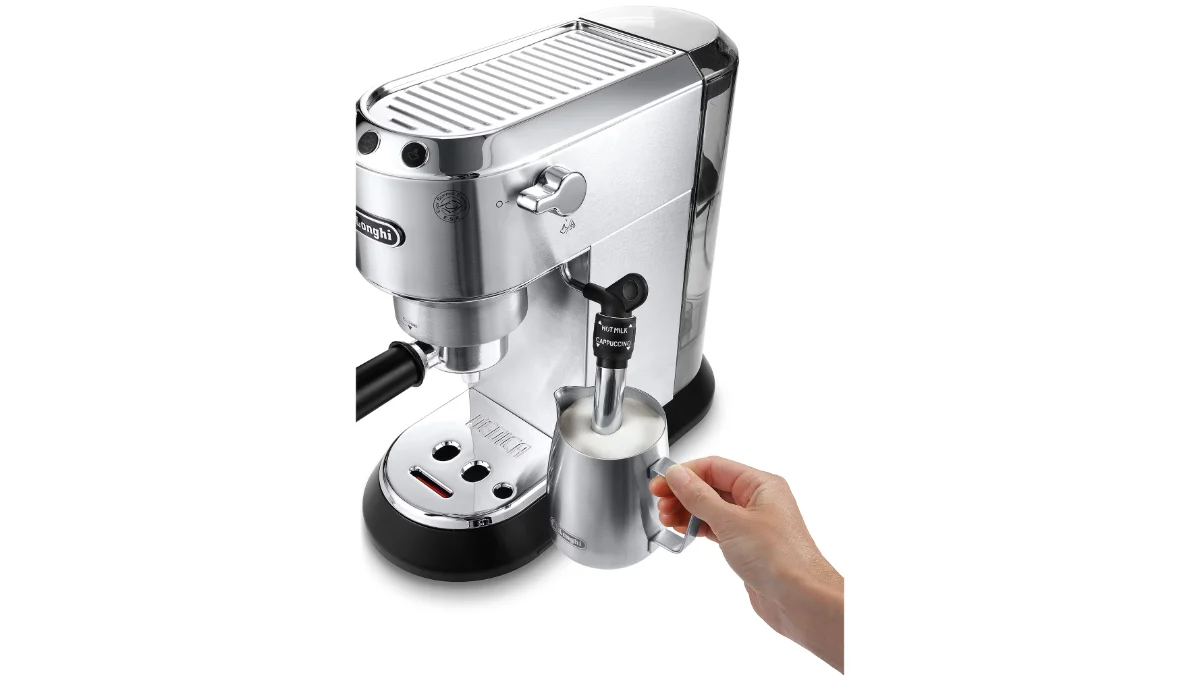 Espressorul De'Longhi Dedica Style EC 685.M argintiu, cu o mână care spumează lapte într-o cană metalică sub duza de abur