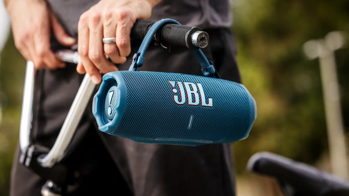 Boxa JBL Charge 6 albastră, agățată de ghidonul unei biciclete cu ajutorul curelei