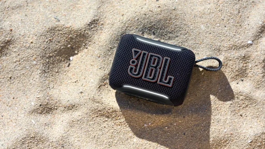 Boxa JBL Go 5, neagră, cu curea, așezată pe nisip la soare