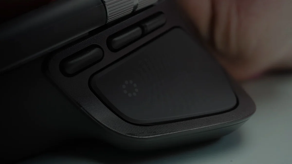 Prim-plan cu panoul haptic de pe suportul pentru degetul mare al mouse-ului Logitech MX Master 4, lângă butoanele înapoi și înainte