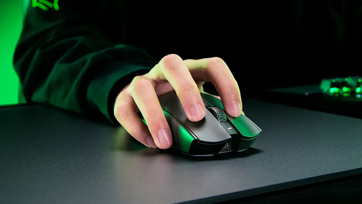Mâna pe mouse-ul Razer Viper V3 Pro negru, într-o priză cu vârfurile degetelor, pe un mousepad negru