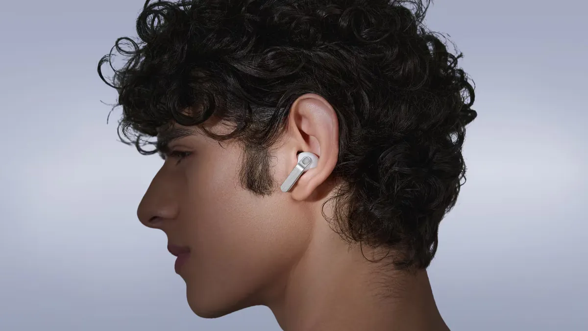 Bărbat tânăr cu părul creț, în profil, cu o cască Samsung Galaxy Buds4 Pro albă, cu lamă argintie, în urechea dreaptă