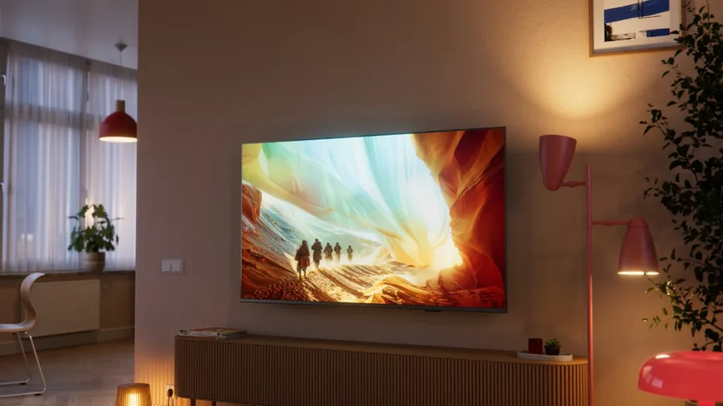 Televizor Philips montat pe perete deasupra unei comode joase, într-un living luminat cald, seara
